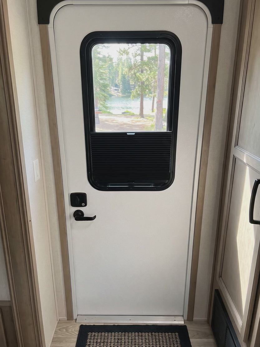 Black cellular shade sliding up inside an RV entry door window